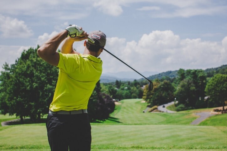 Golfer swinging golf club at golf course | The Grove Frisco, TX