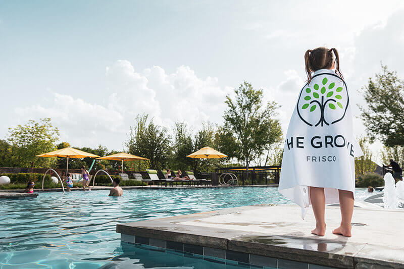 Kid in towel at swimming pool in The Grove Frisco community